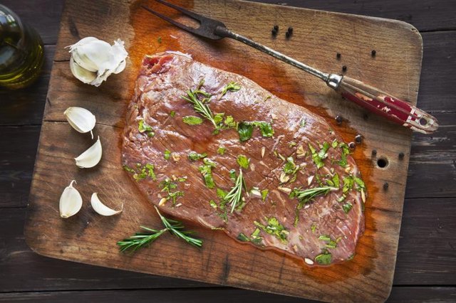 Raw Marinated Flank Steak on an old cutting board