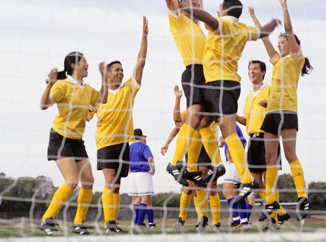 Mixed Football team celebrating goal at goal mouth, surface view