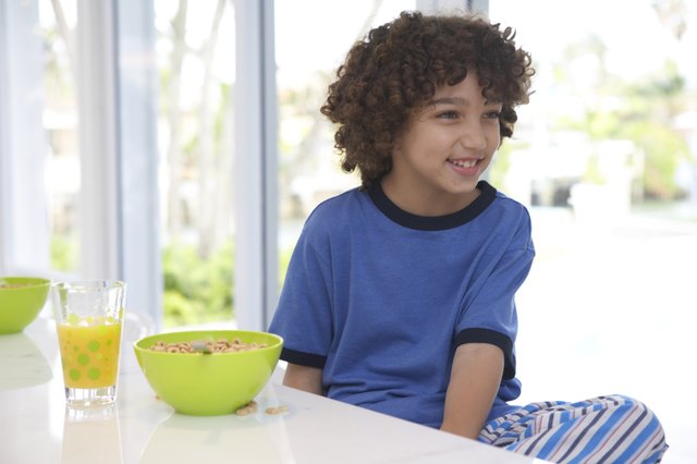 Boy (8-10) at breakfast table, smiling