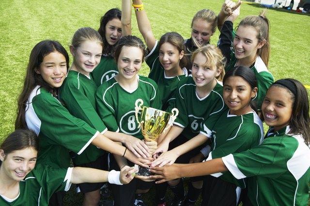 Girls (12-15) football team holding trophy, smiling, elevated view