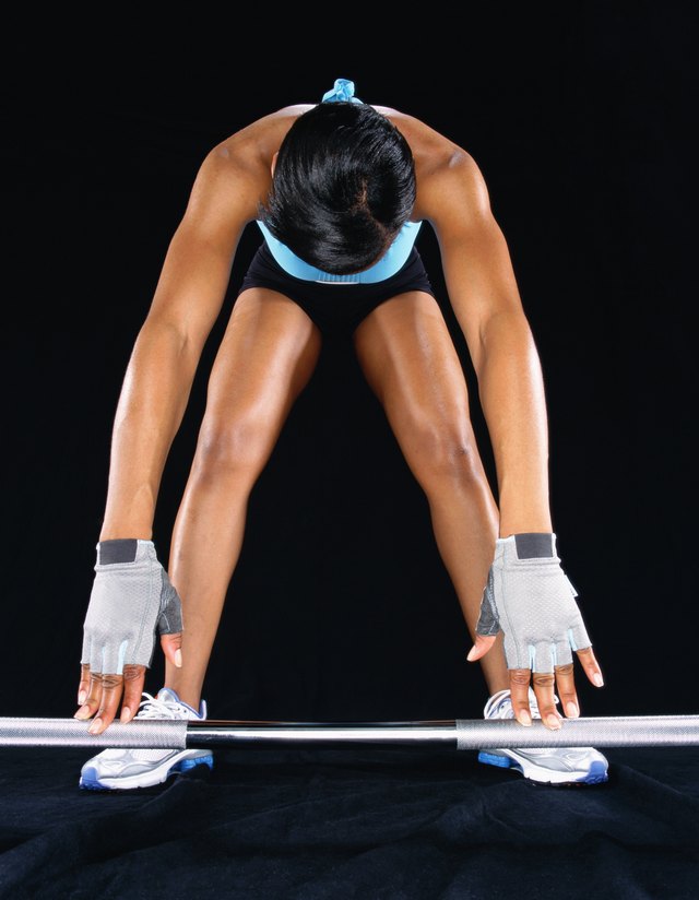 Young woman leaning down to pick up barbell