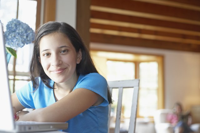 Portrait of a teenage girl leaning on a laptop