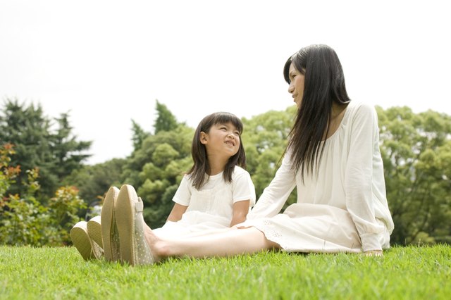Mother and daughter sitting outside together on a lawn