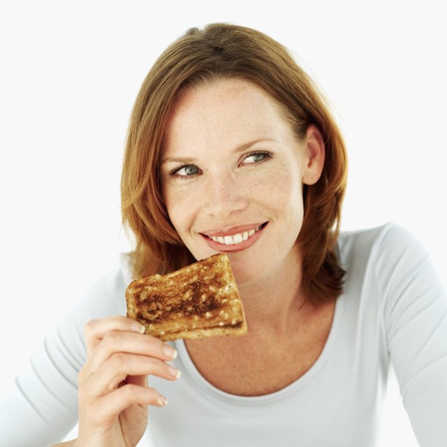 Young woman smiling eating a slice of toast