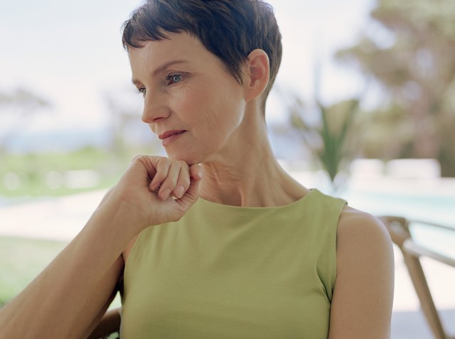 Mature woman resting chin on hand, staring downwards, close-up