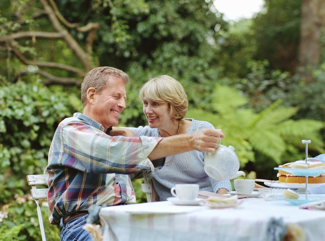 Couple at garden table, man pouring tea