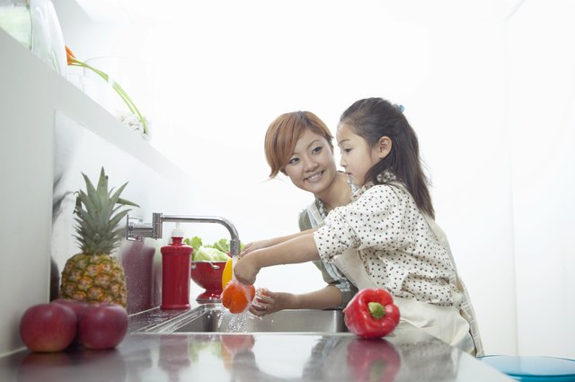 Mother and Daughter Washing Peppers at a Kitchen Sink