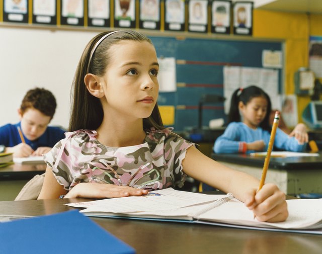 Young Girl Writing in Her Exercise Book in the Classroom