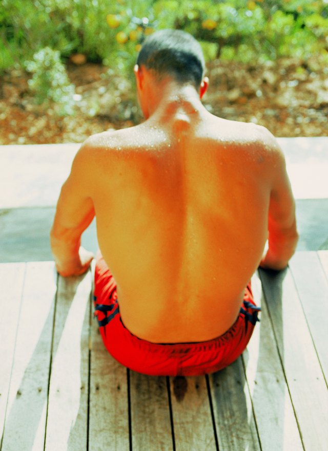 Rear view of a young man sitting on the edge of a wooden platform