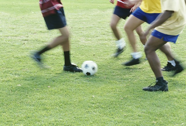 People playing football outdoors,low section
