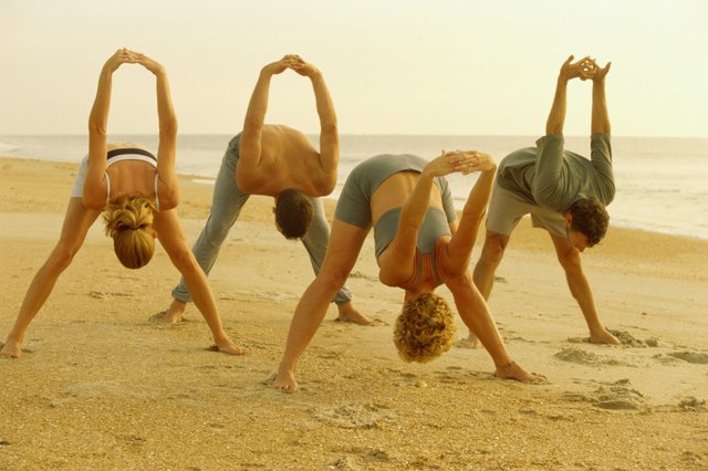 Group of people performing yoga on the beach