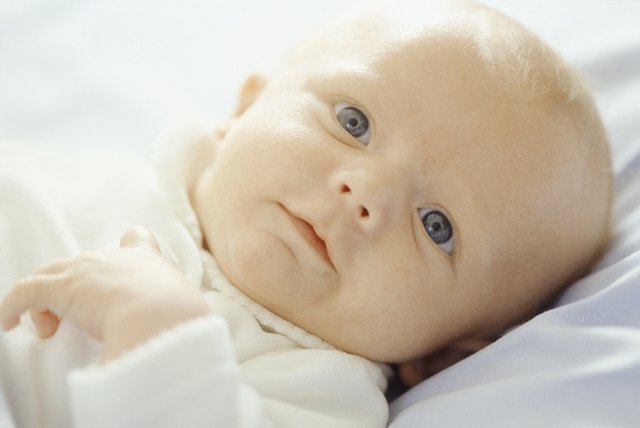 Baby (3-6 months) lying on white sheets, close-up