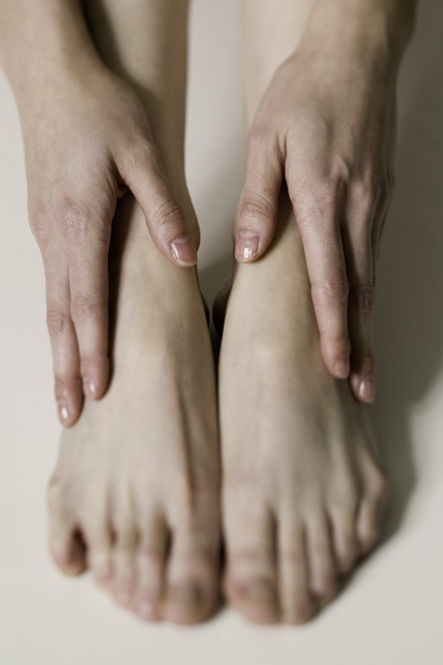 Woman holding hands on feet, close up of feet,, close-up