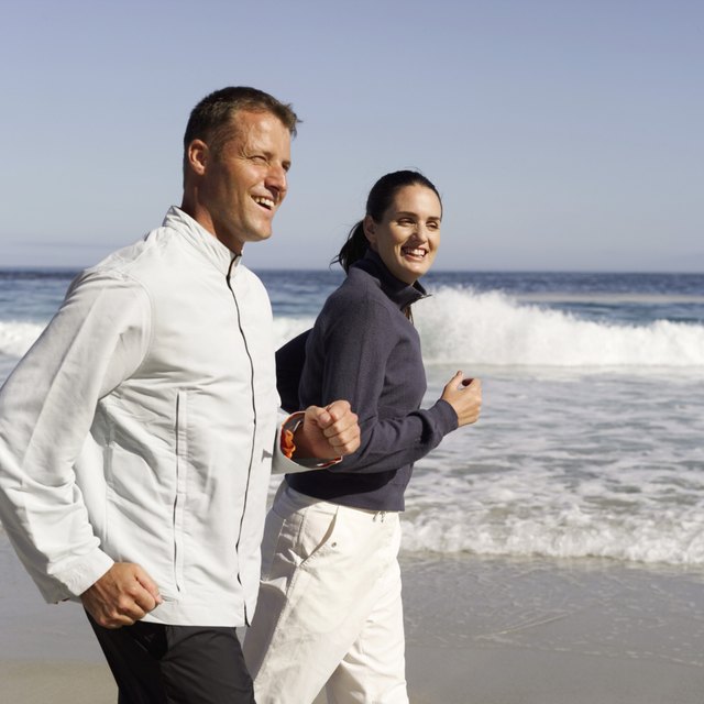 side view of a couple jogging on the beach