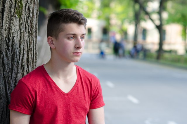Handsome young man standing beside tree in spring