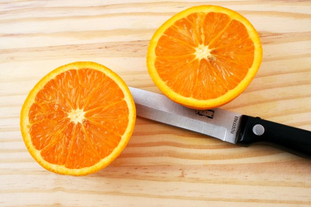 Two halves of an orange and a knife on a tray