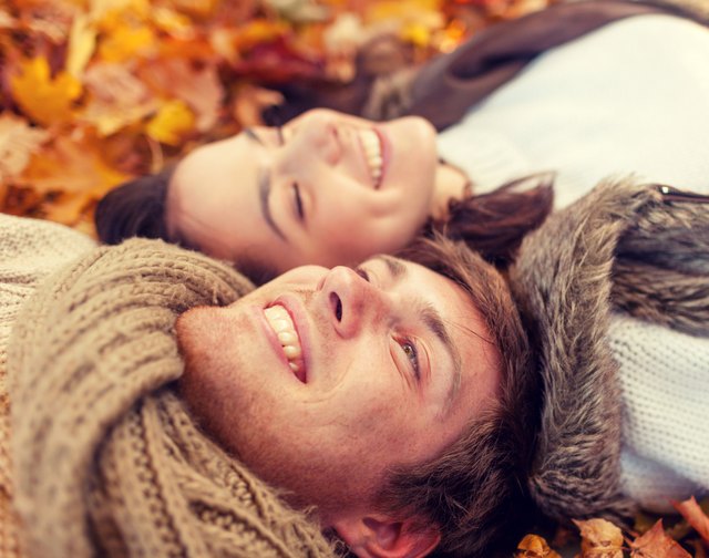 close up of smiling couple lying in autumn park