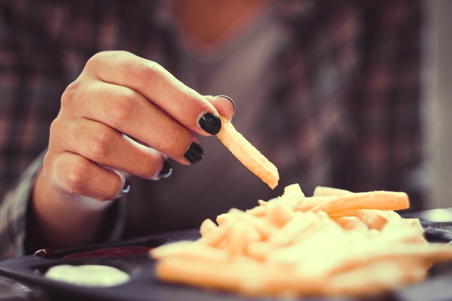 woman hand with green nails toasting french fries in restaurant