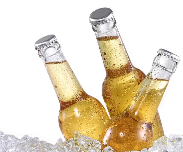 Three dewy beer bottles on ice