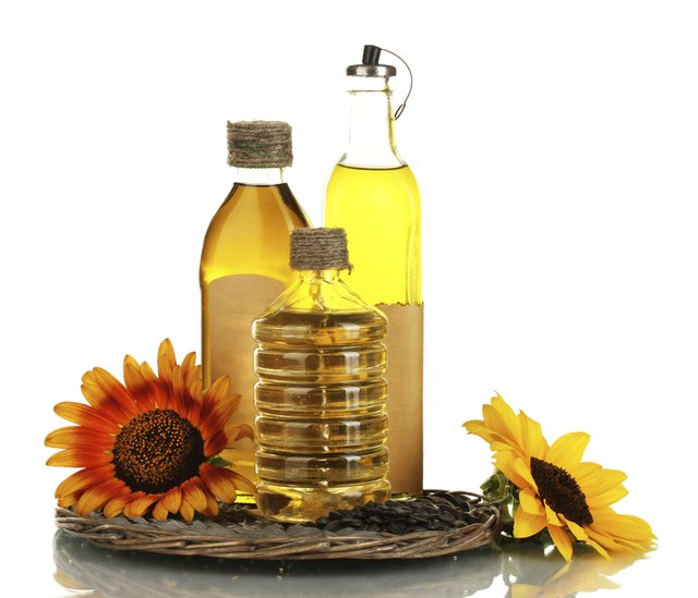 oil in bottles, sunflowers and seeds isolated on white