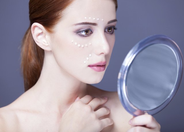 women with cosmetic cream on a chee