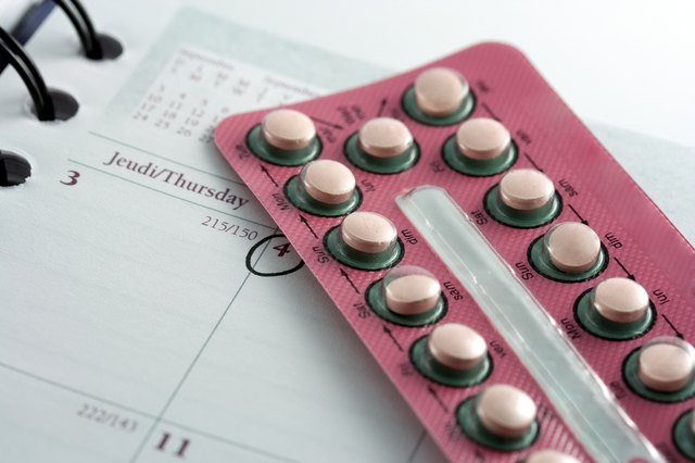 Birth control pills on top of a calendar with date circled