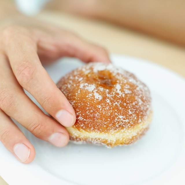 Close-up of a young man's hand holding a doughnut