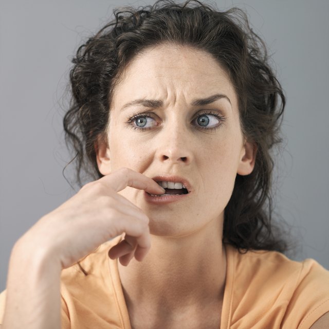 Young woman with finger in mouth, close-up, studio shot