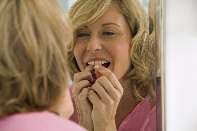 Mid adult woman flossing her teeth