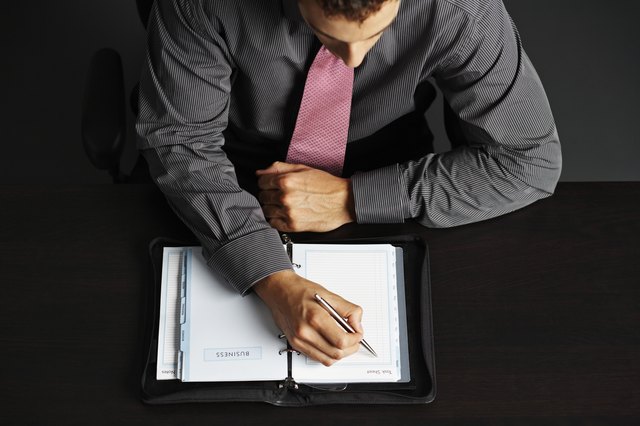 Businessman Writing in Daily Organizer
