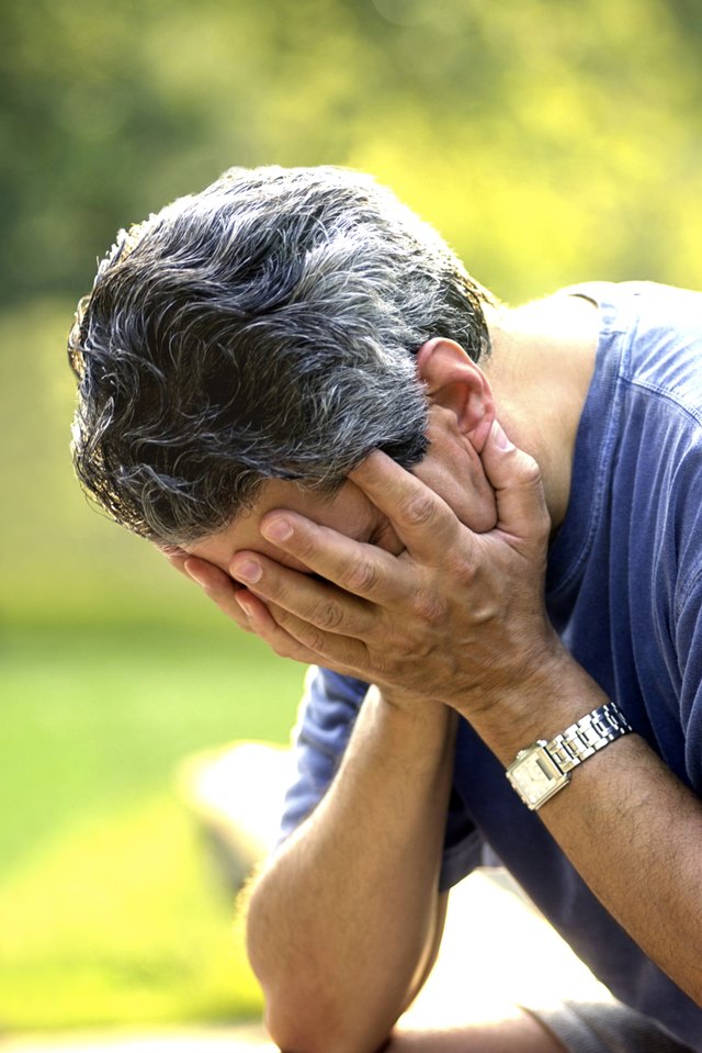 Close-up of a man with his face buried in his hands.