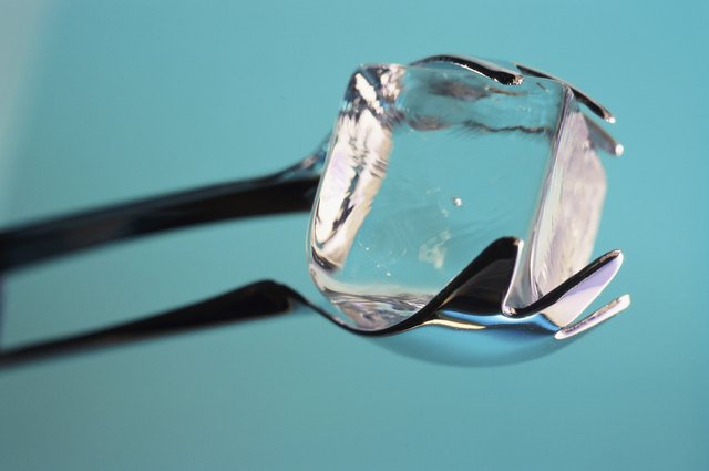 Close-up of an ice cube held by tongs