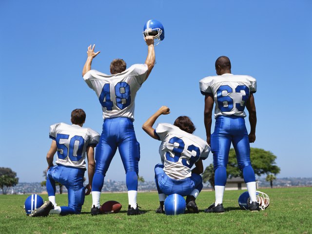 rear view of four football players on a football field