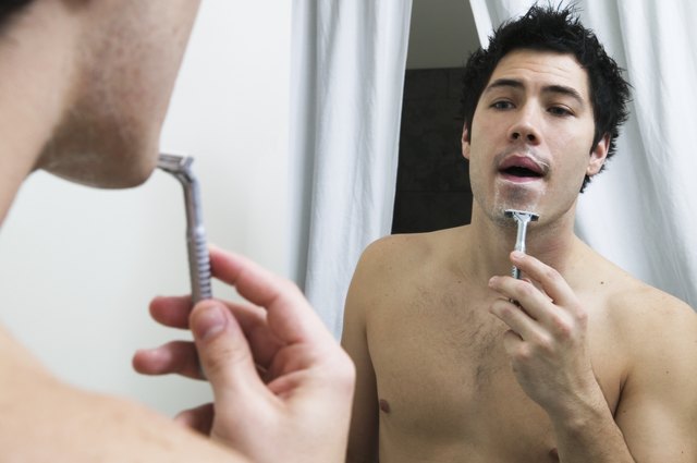 Young man shaving with a razor