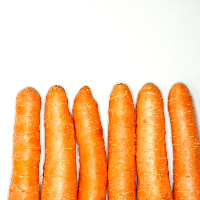Six raw carrots in row, close-up