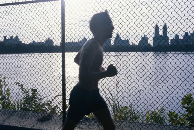 Bare-chested man running outdoors, side view