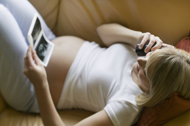 Pregnant woman using phone, on sofa in living room
