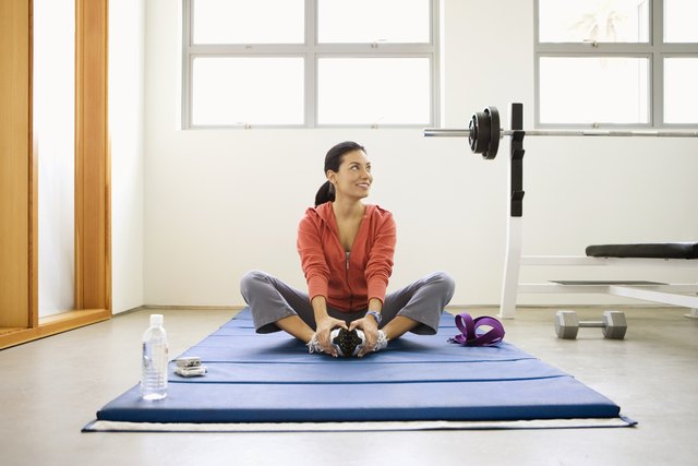 Woman doing stretching exercises on mat in gym