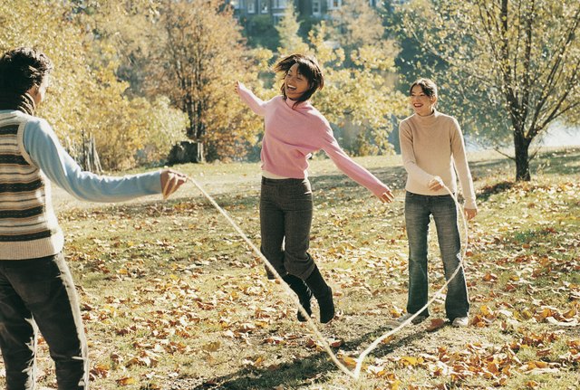Three Adults Skipping With a Rope in a Park in Autumn