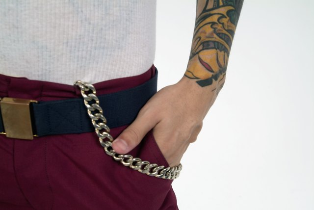 Mid section image of man's hand in pocket; man has tattoo and chain on pants, close-up