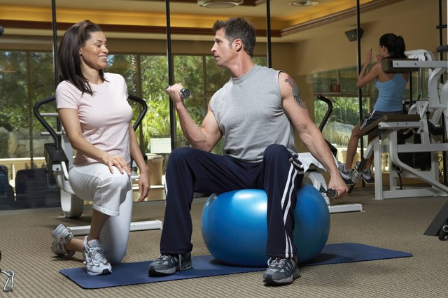 Woman instructor looking at man lifting weights