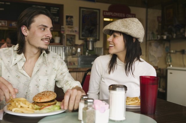 Happy couple in diner together with burger and fries