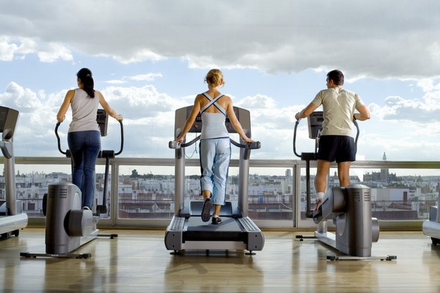 Rear view of People using exercise equipment in front of a window