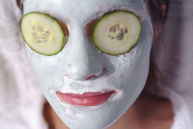 Close-up of a mid adult woman wearing a facial mask with cucumber slices on her eyes