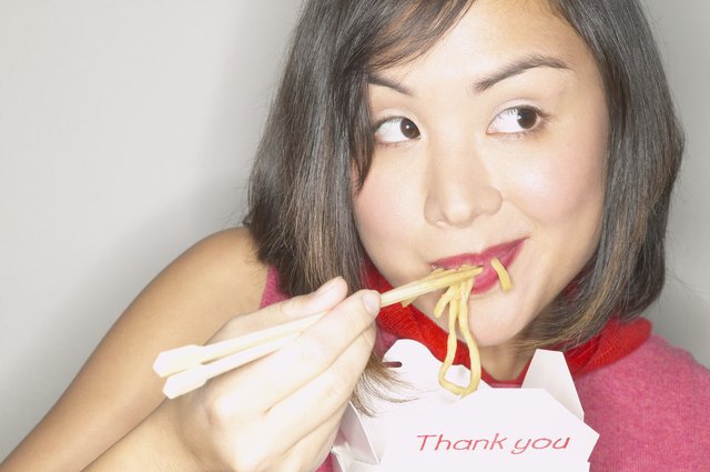 Young woman smiling eating noodles