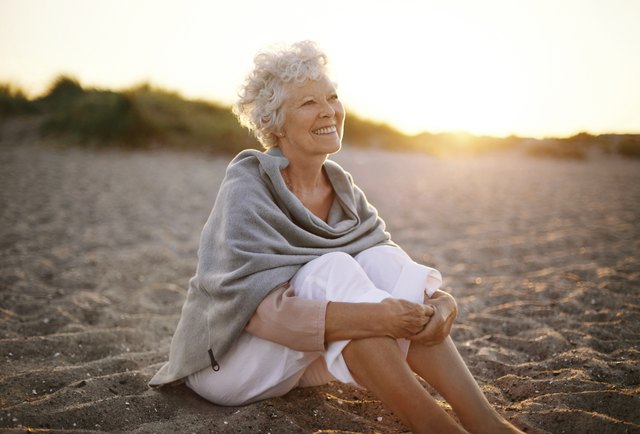 Cheerful old woman sitting on the beach