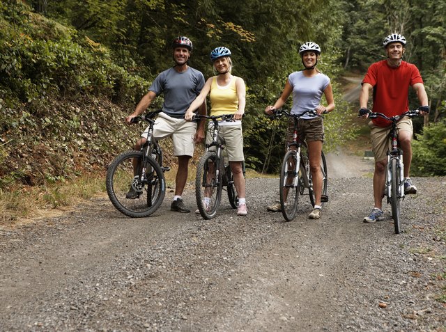 Four adults on mountain bikes on dirt road, portrait