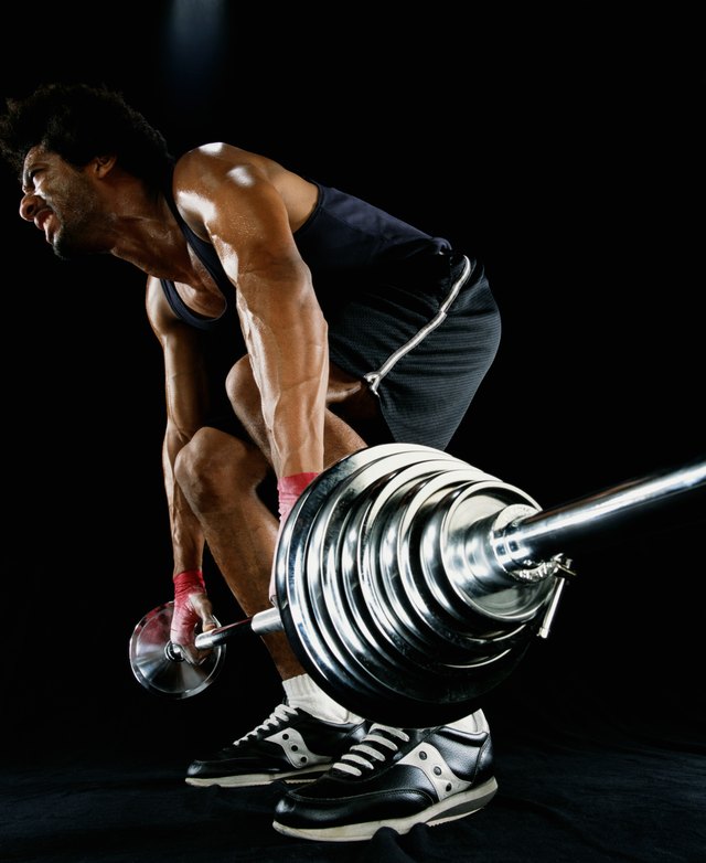 Young man lifting barbell, low angle view