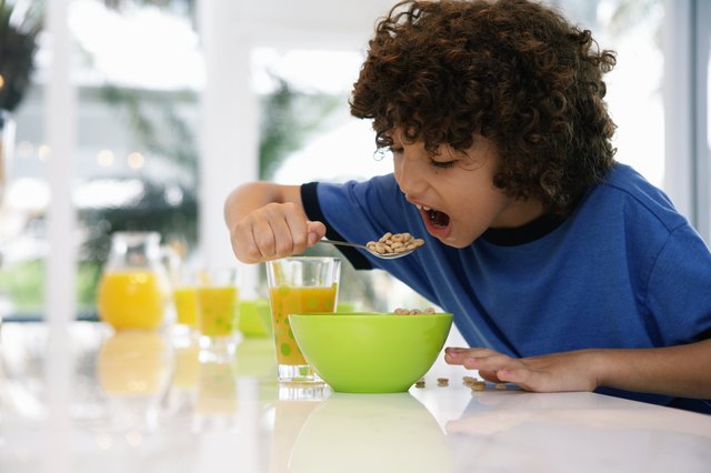 Boy (8-10) at table, eating cereal