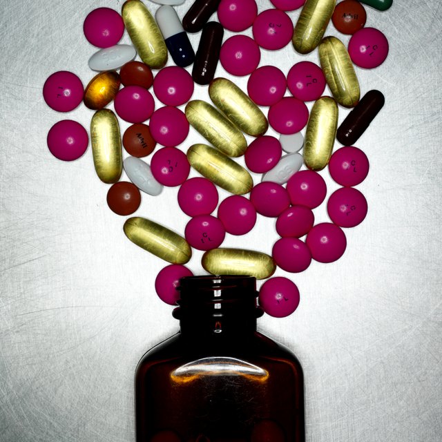 Assorted coloured pills by pill bottle, close up